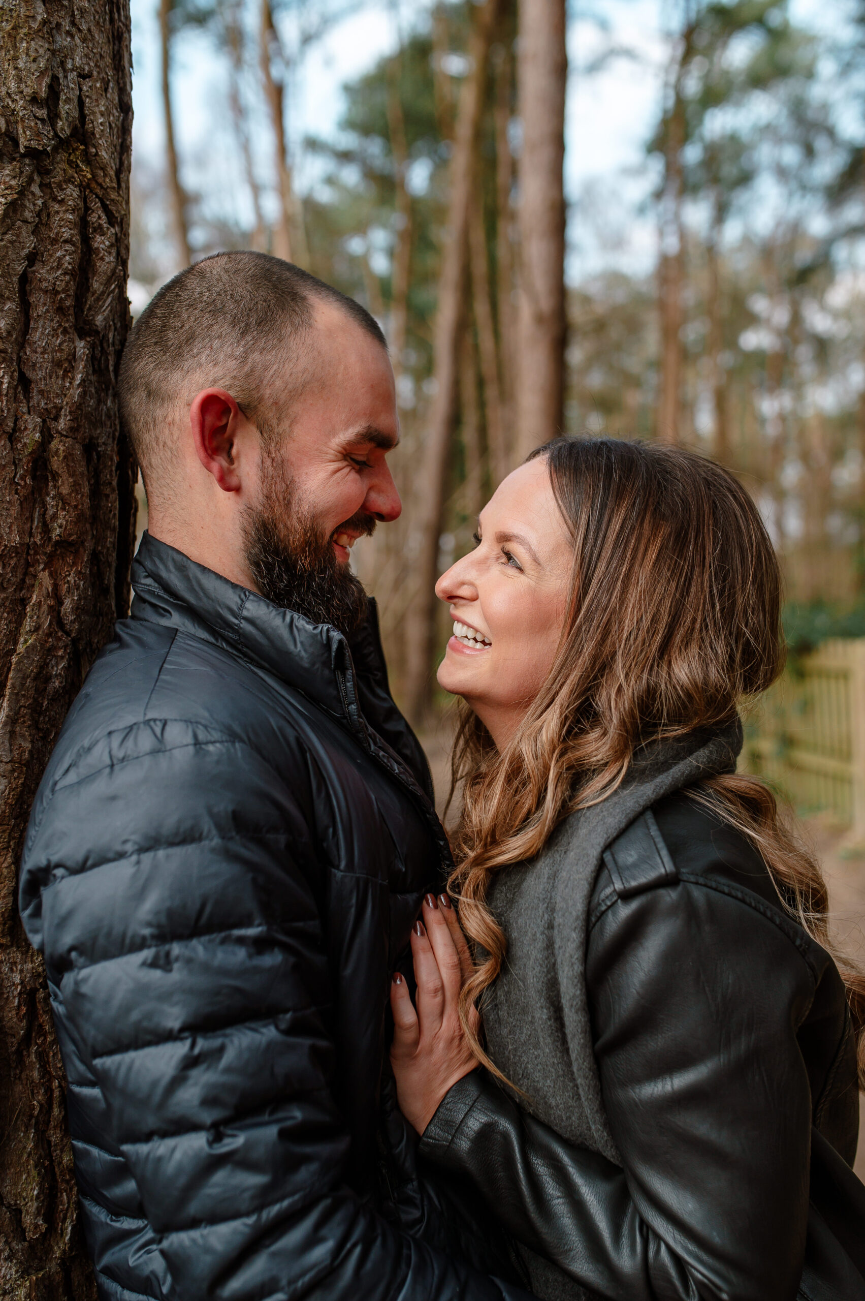 Tom and Chelsey laugh whilst looking into each others eyes on their shoot in oakley woods