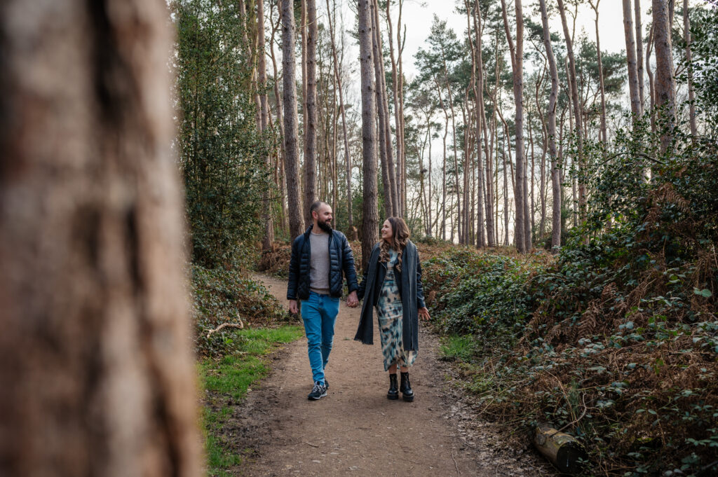 Couple walking holding hands through oakley woods near leamington spa, warwickshire on their pre-wedding shoot