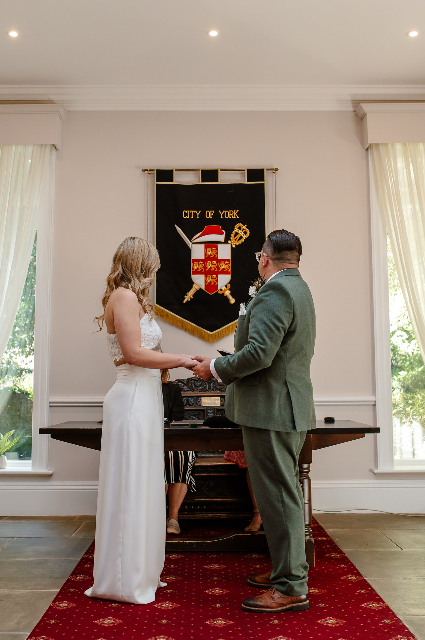 bride and groom holding hands facing each other during the ceremony at york registry office 