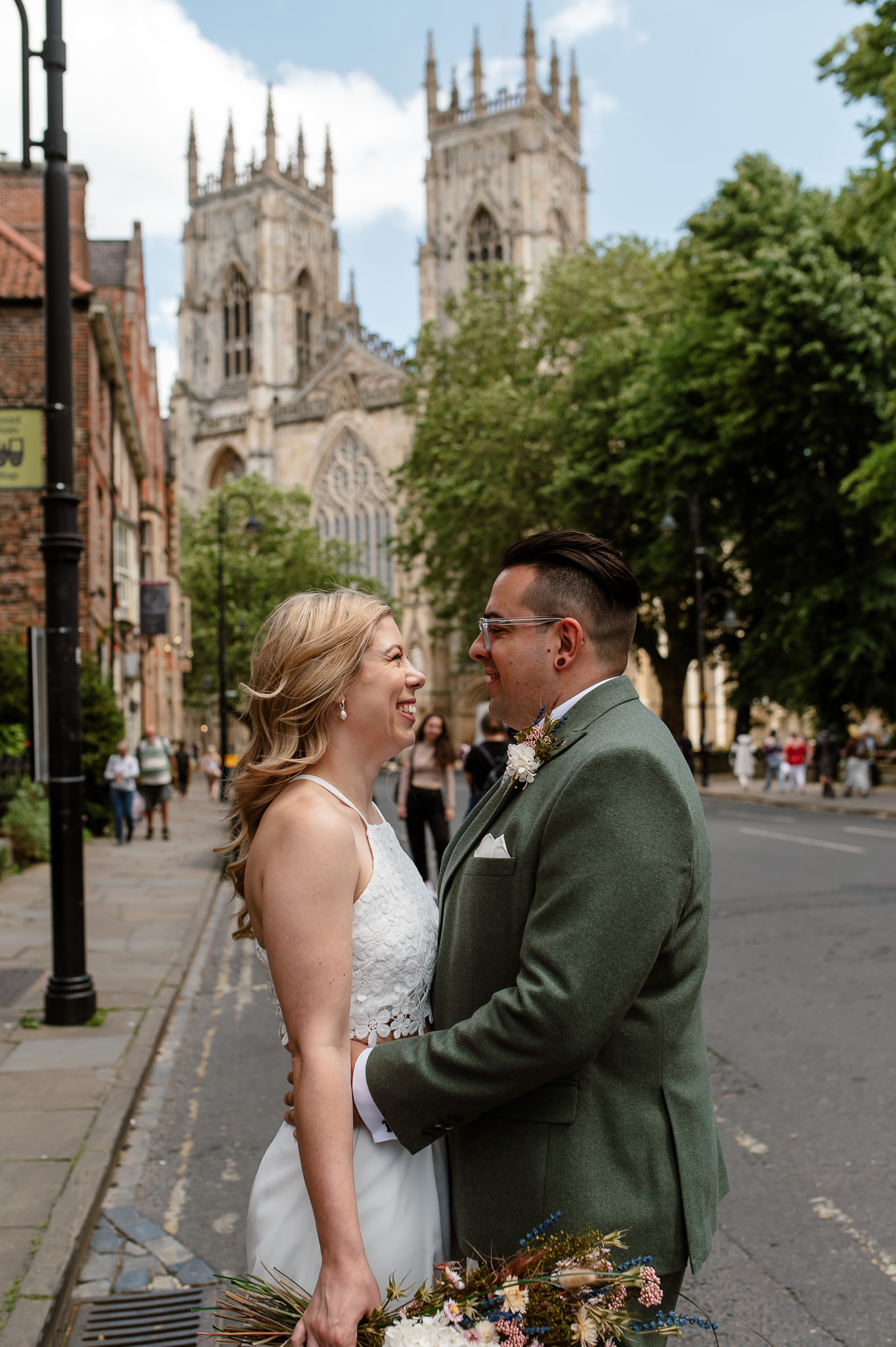 bride and groom looking at eachother smiling in front of york minster 