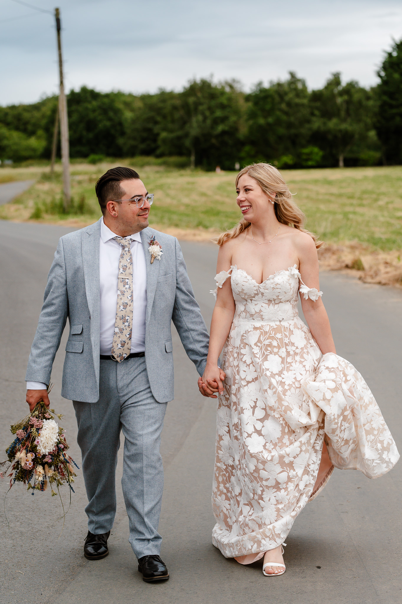 bride and groom walking hand in hand looking at each other 