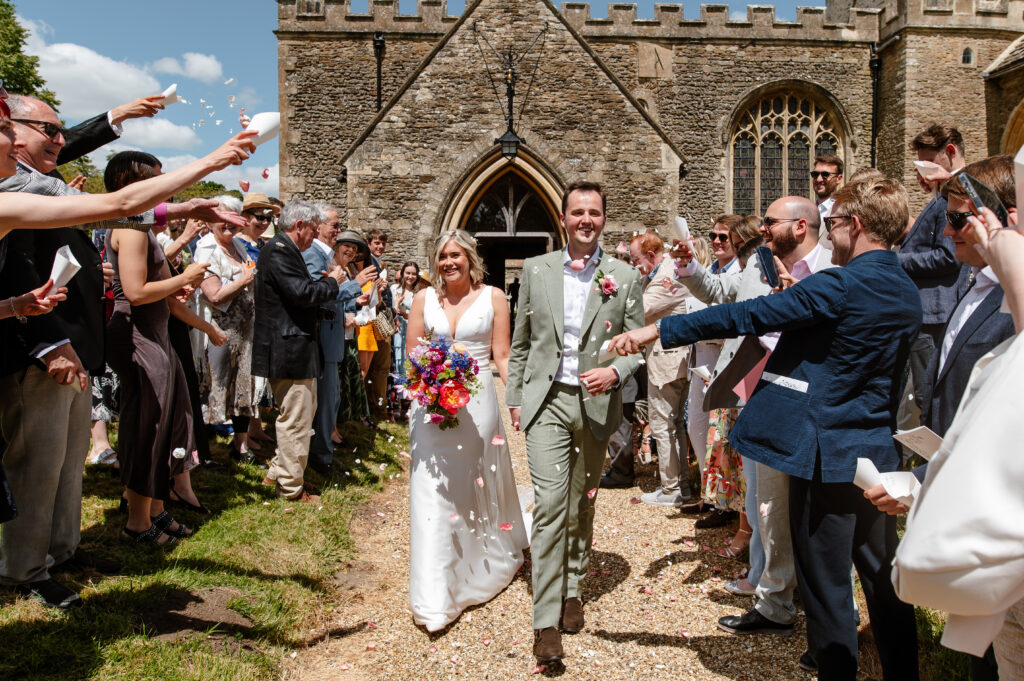 wedding confetti exit - couple leaving the church with their guests surrounding them with confetti